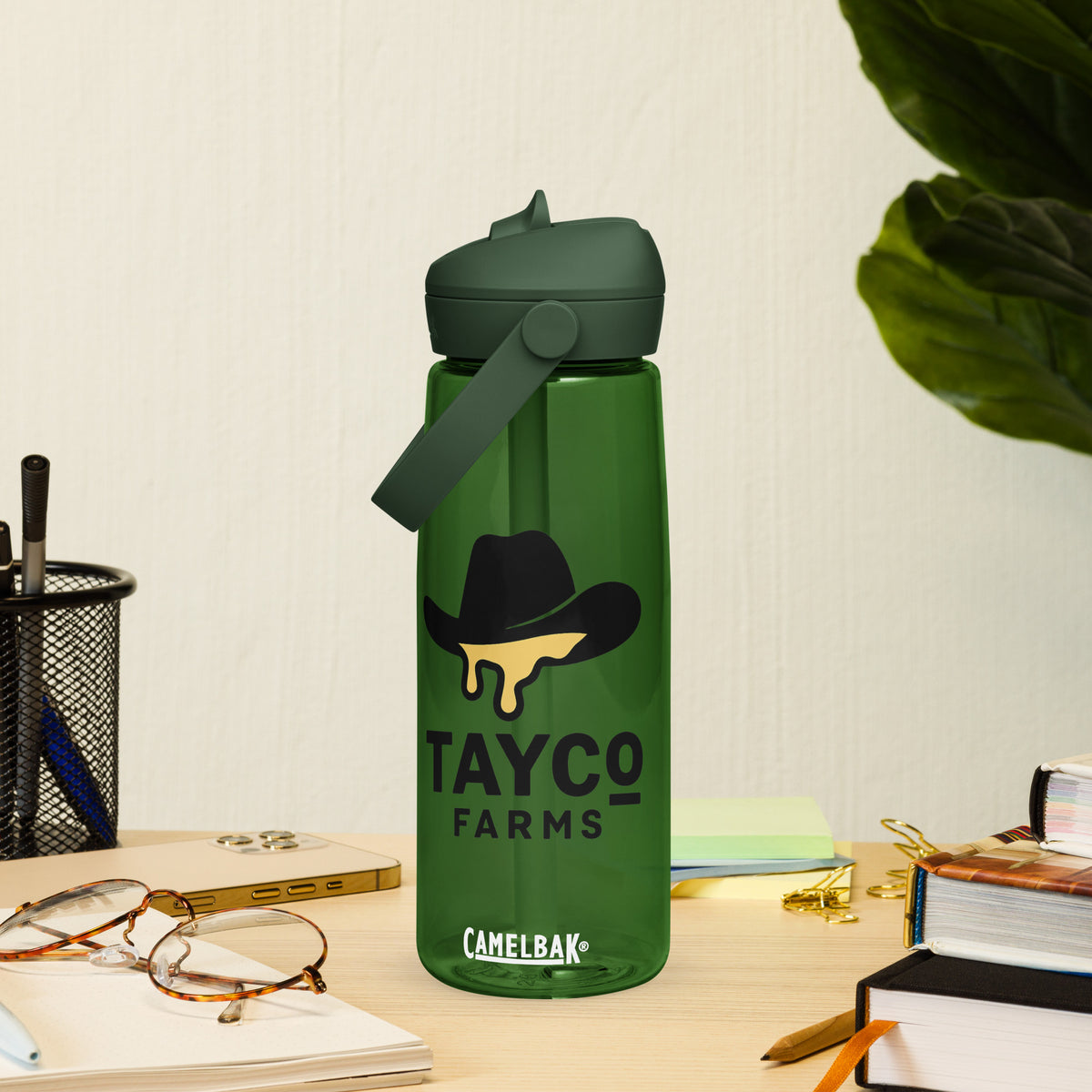 Tayco Farms forest green water bottle beside a notebook
