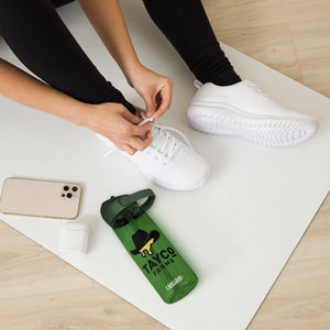 Tayco Farms forest green water bottle beside a person tying white shoes