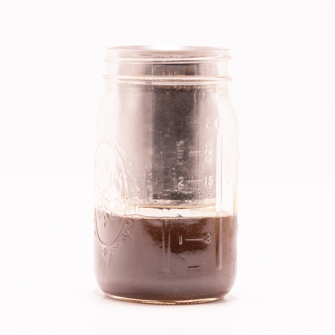 Glass jar containing dark infused liquid