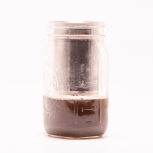 Glass jar containing dark infused liquid