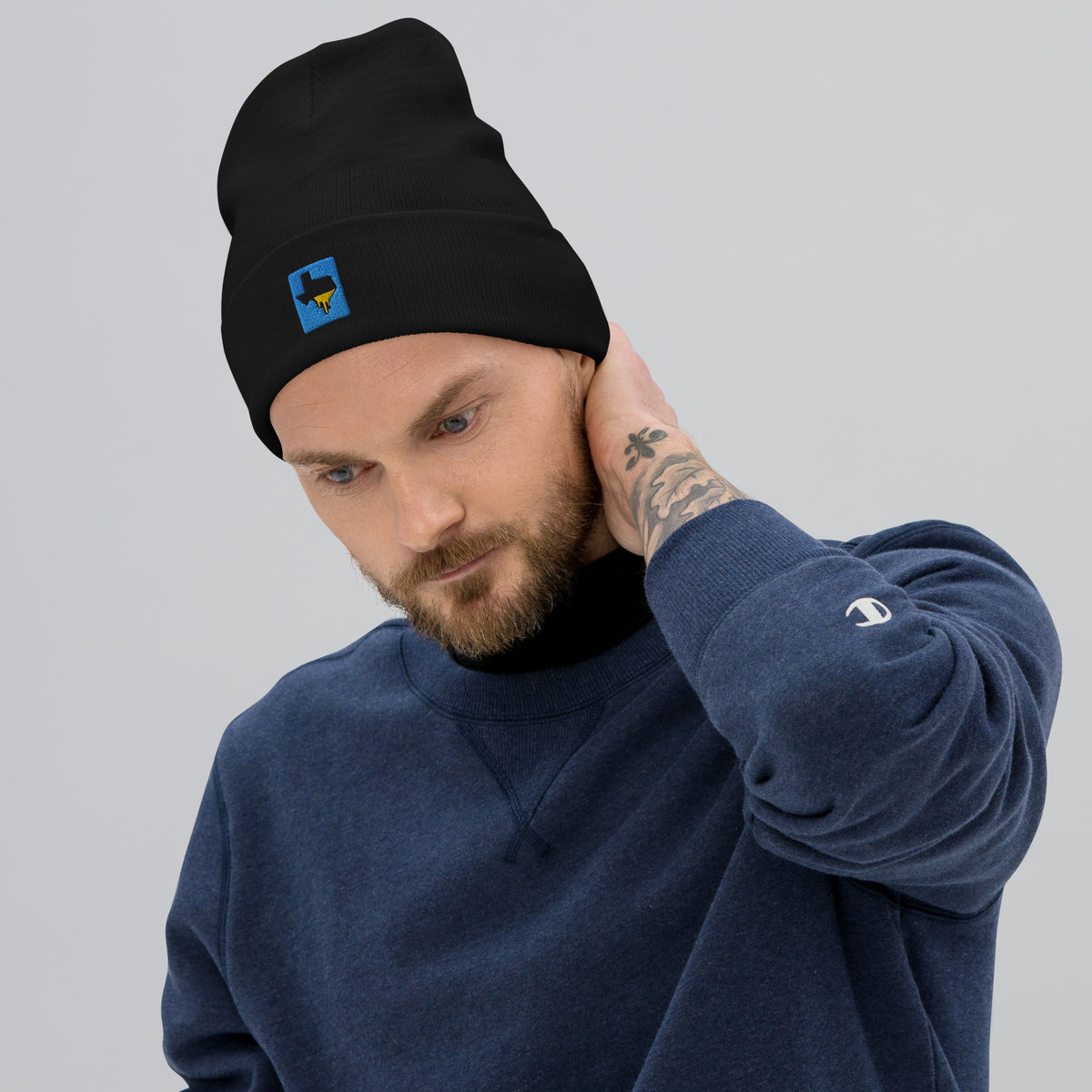 Person wearing a black Tayco Farms embroidered Texas logo beanie